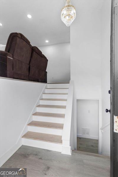 stairs with visible vents, recessed lighting, and a notable chandelier