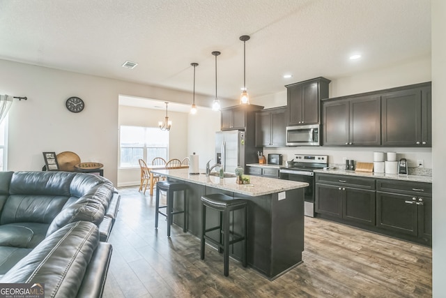 113 Hamlet Ct, Hinesville, GA 31313 - kitchen with dark wood-style flooring, visible vents, open floor plan, a breakfast bar, and stainless steel appliances