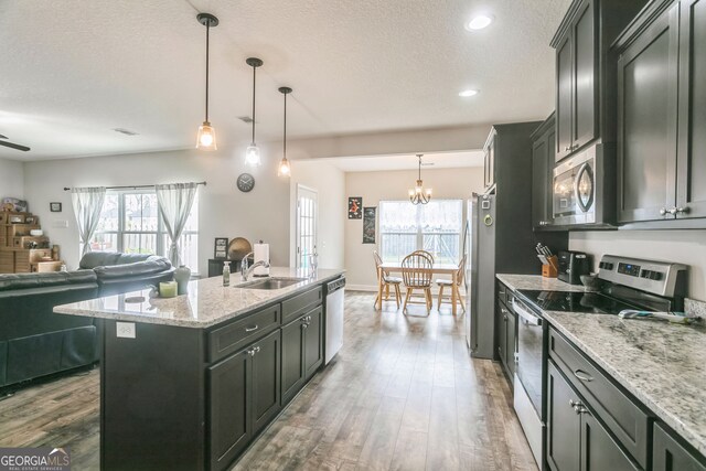 113 Hamlet Ct, Hinesville, GA 31313 - kitchen with appliances with stainless steel finishes, a textured ceiling, dark wood-style flooring, open floor plan, and a center island with sink