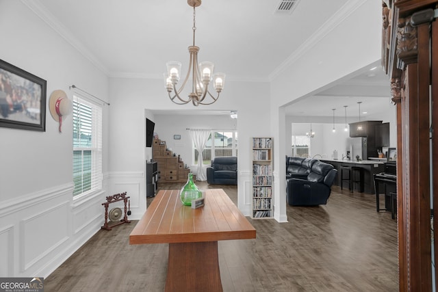 113 Hamlet Ct, Hinesville, GA 31313 - dining area featuring a chandelier, dark wood finished floors, crown molding, wainscoting, and stairs