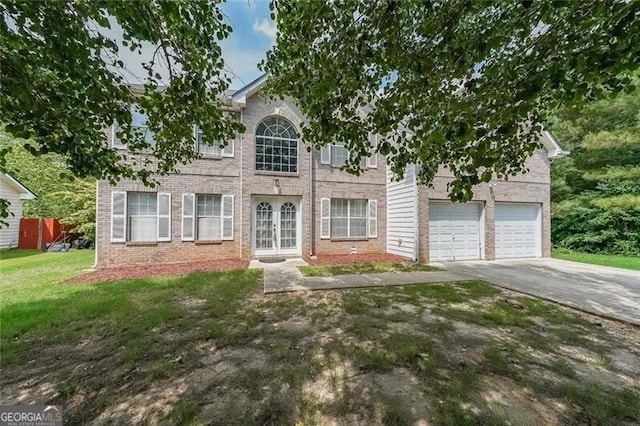 view of front of property with french doors, a front yard, a garage, brick siding, and aphalt driveway