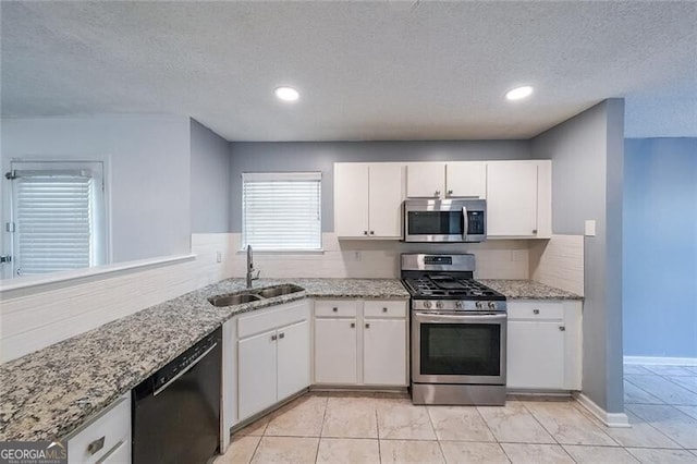 kitchen featuring white cabinets, stainless steel appliances, a textured ceiling, and a sink