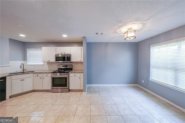 1528 Rogers Crossing Dr, Lithonia, GA 30058 - kitchen featuring appliances with stainless steel finishes, white cabinets, light stone counters, a textured ceiling, and light tile patterned flooring