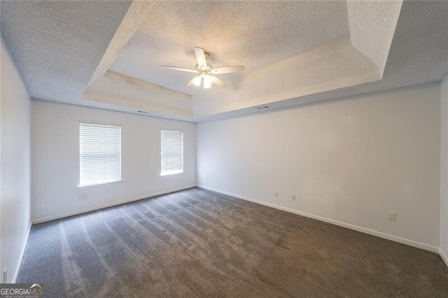 empty room with carpet, a tray ceiling, and a textured ceiling