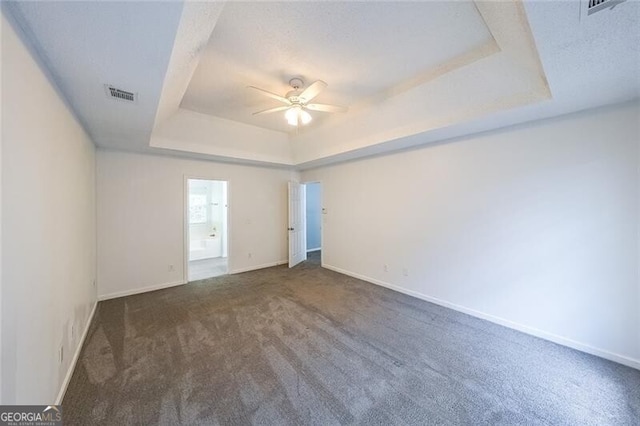carpeted spare room featuring baseboards, ceiling fan, a tray ceiling, and visible vents