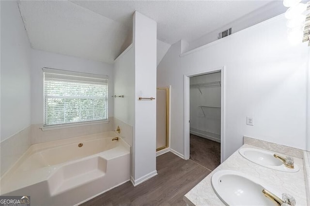full bathroom featuring lofted ceiling, a sink, a bath, and wood finished floors