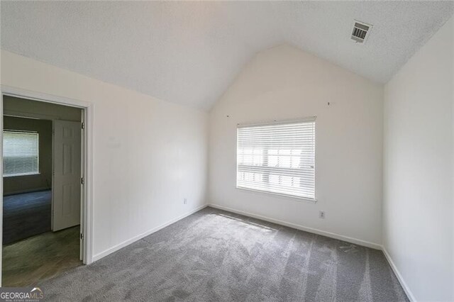 empty room with carpet flooring, baseboards, and lofted ceiling