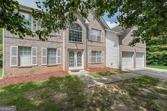 view of front facade featuring brick siding, french doors, a front yard, and concrete driveway