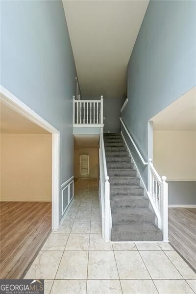 stairway featuring a towering ceiling and wood finished floors