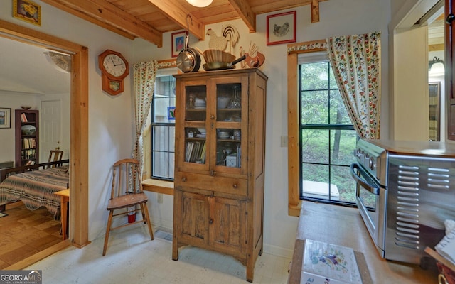 interior space featuring wooden ceiling, light floors, baseboards, and beamed ceiling