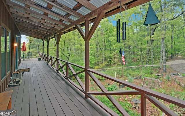 wooden terrace featuring a garden