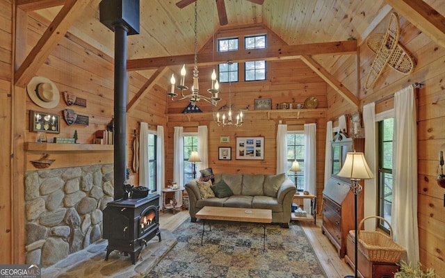 living room featuring a wood stove, hardwood / wood-style flooring, high vaulted ceiling, wooden walls, and a wealth of natural light