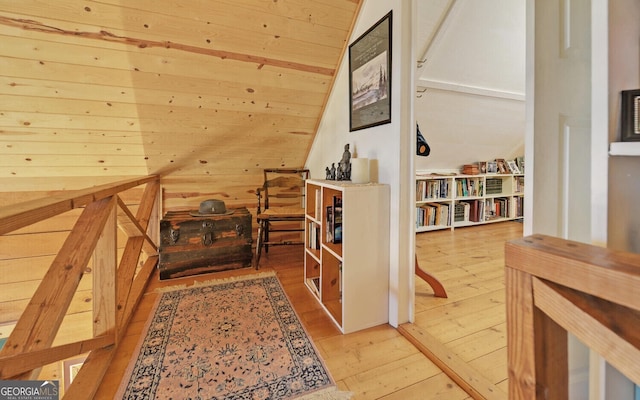 additional living space with light wood-type flooring and wooden walls