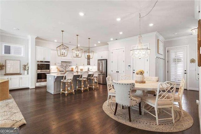 dining area with dark wood finished floors, ornamental molding, recessed lighting, and a notable chandelier