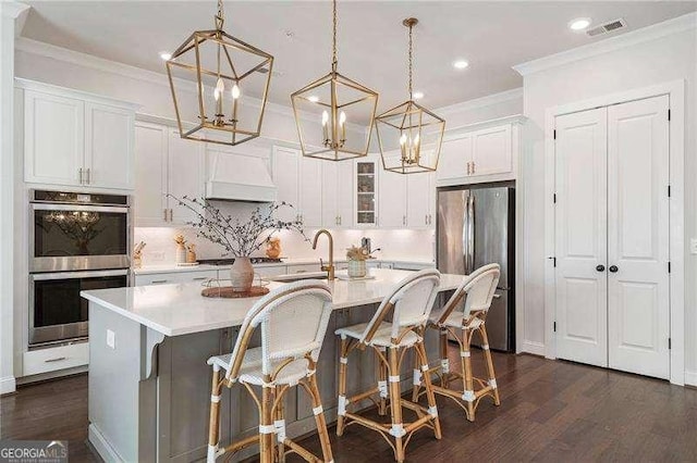 kitchen with crown molding, premium range hood, a sink, a notable chandelier, and stainless steel appliances