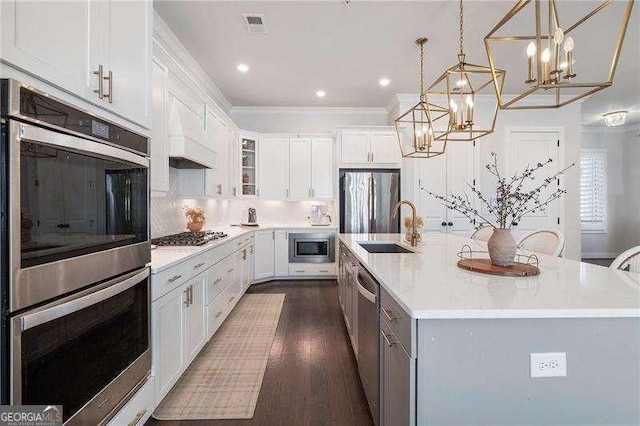 kitchen with a sink, light countertops, dark wood-style floors, a notable chandelier, and stainless steel appliances