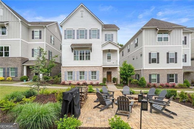 back of property featuring board and batten siding, a patio, and an outdoor fire pit