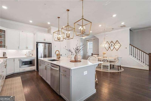 kitchen with a sink, a chandelier, ornamental molding, and stainless steel appliances