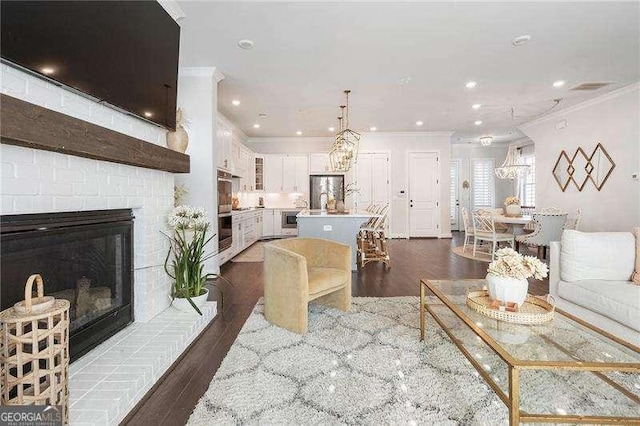 living area with ornamental molding, a brick fireplace, and dark wood-style flooring
