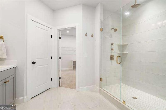 full bathroom with vanity, baseboards, a walk in closet, and a stall shower