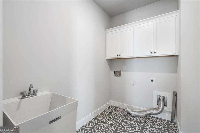 clothes washing area with electric dryer hookup, a sink, cabinet space, and baseboards