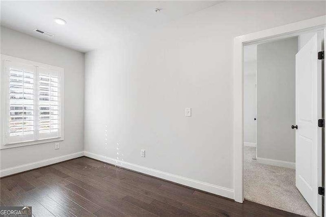 unfurnished room featuring dark wood-style flooring, baseboards, and visible vents