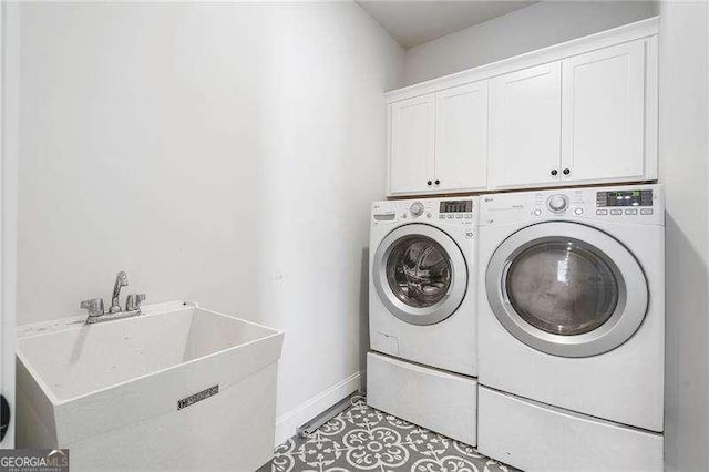 laundry room featuring independent washer and dryer, cabinet space, a sink, baseboards, and light tile patterned floors