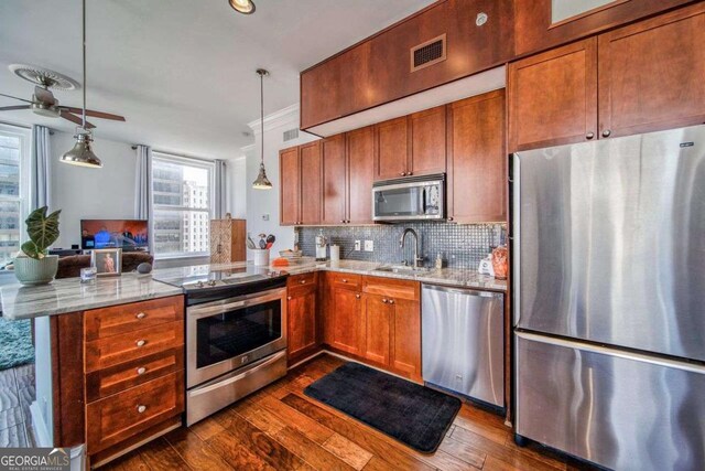 kitchen with a sink, dark wood-style flooring, a peninsula, and stainless steel appliances
