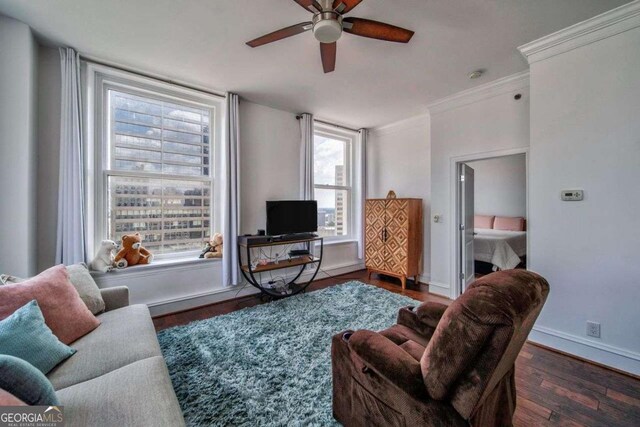 living area featuring crown molding, baseboards, ceiling fan, and wood finished floors