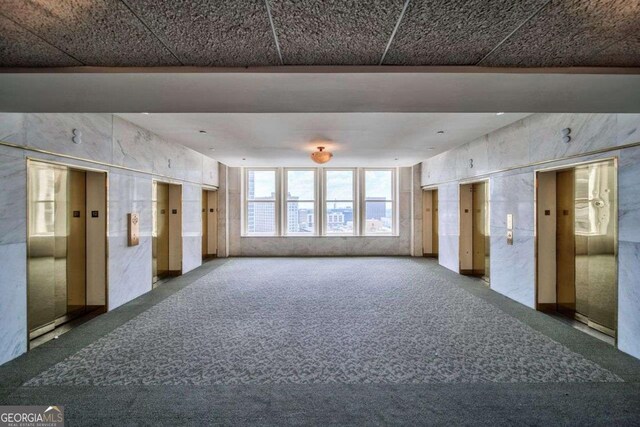 carpeted spare room featuring elevator