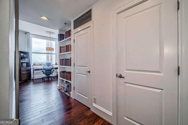 corridor with dark wood finished floors and built in shelves