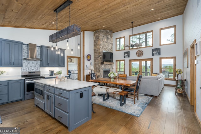454 N Old Aska Rd, Blue Ridge, GA 30513 - kitchen featuring wooden ceiling, wall chimney range hood, a high ceiling, appliances with stainless steel finishes, and a stone fireplace