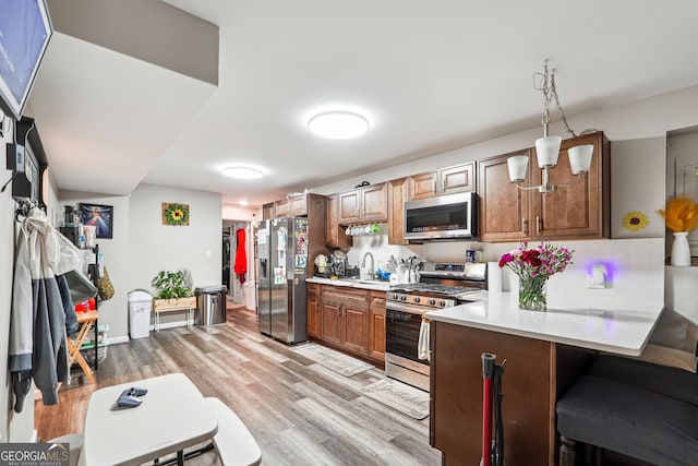 1366 Maple Ridge Dr, Suwanee, GA 30024 - kitchen with appliances with stainless steel finishes, light countertops, a sink, light wood finished floors, and a peninsula