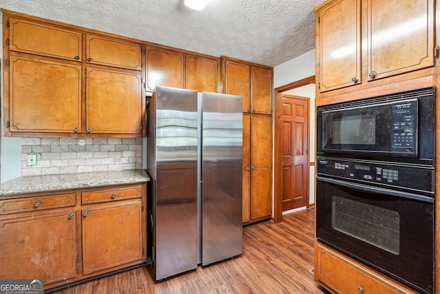1366 Maple Ridge Dr, Suwanee, GA 30024 - kitchen featuring brown cabinetry, light stone counters, light wood-style flooring, backsplash, and black appliances