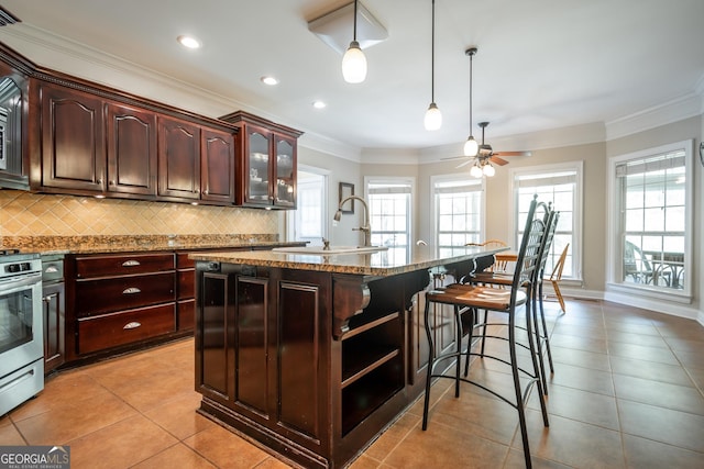 229 Deer Haven Run, Carlton, GA 30627 - kitchen with backsplash, a breakfast bar area, a kitchen island with sink, and a healthy amount of sunlight