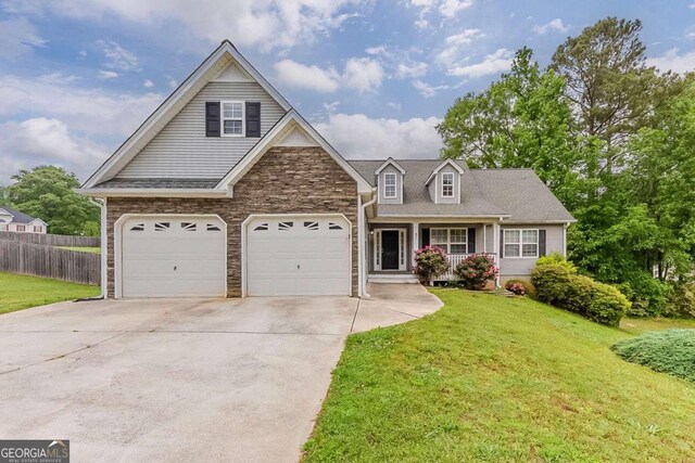 view of front of home with a front lawn, fence, stone siding, a porch, and driveway