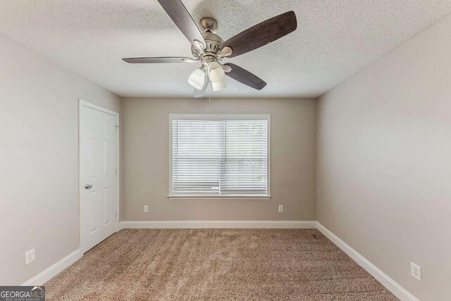spare room with baseboards, carpet, a textured ceiling, and ceiling fan