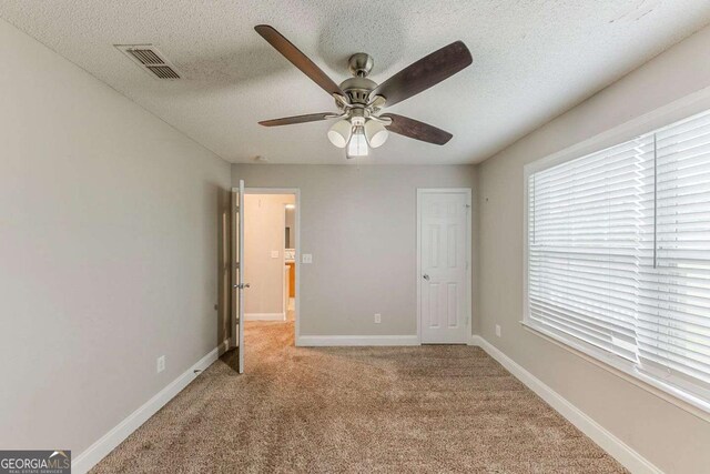 unfurnished bedroom with carpet floors, visible vents, baseboards, ceiling fan, and a textured ceiling