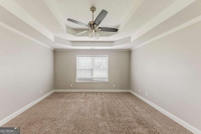 empty room with carpet floors, a ceiling fan, a textured ceiling, and a raised ceiling