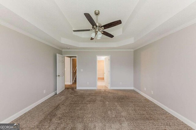 unfurnished bedroom featuring carpet floors, baseboards, a raised ceiling, and ensuite bath