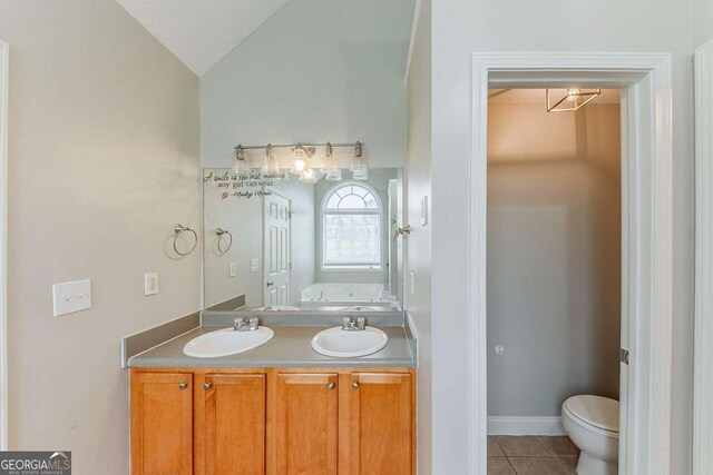 bathroom featuring a sink, a bath, tile patterned floors, and vaulted ceiling