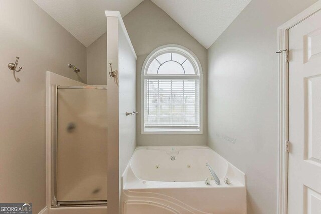 full bath featuring a whirlpool tub, lofted ceiling, and a stall shower