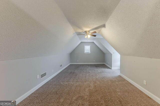 bonus room with a ceiling fan, a textured ceiling, visible vents, lofted ceiling, and carpet flooring