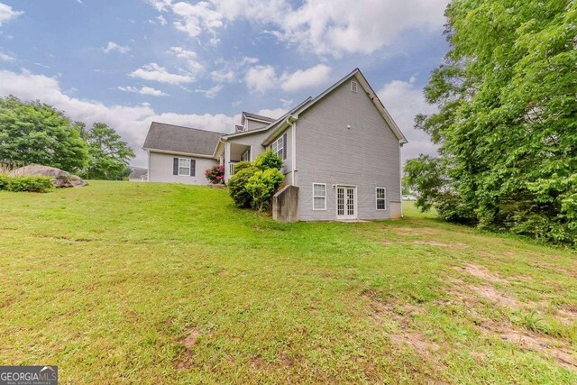 rear view of house with a lawn and french doors