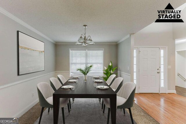 dining area featuring crown molding, a notable chandelier, a textured ceiling, baseboards, and wood finished floors