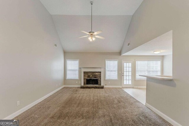 unfurnished living room featuring a healthy amount of sunlight, high vaulted ceiling, baseboards, and light carpet