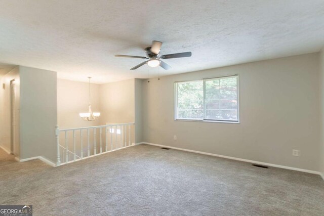 carpeted empty room with baseboards, visible vents, and ceiling fan with notable chandelier