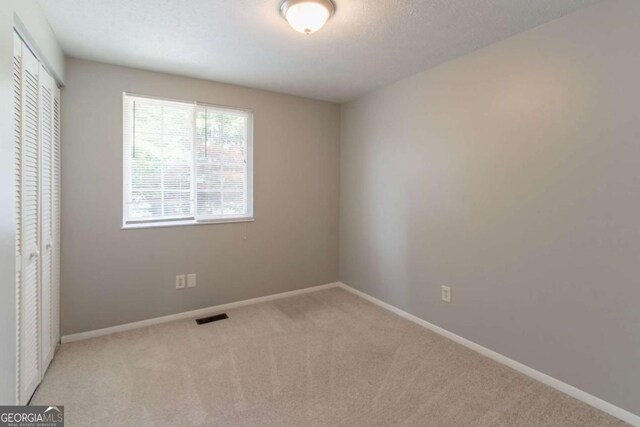 unfurnished bedroom featuring visible vents, carpet flooring, baseboards, and a closet