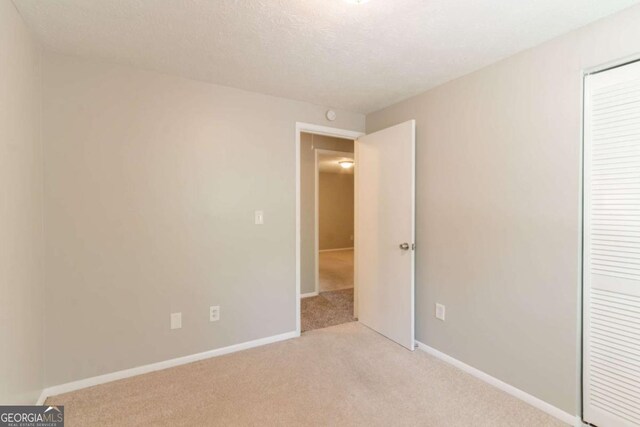 unfurnished bedroom featuring carpet floors, baseboards, and a closet
