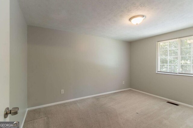 unfurnished room featuring baseboards, carpet flooring, and a textured ceiling